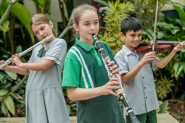 three students playing instruments - flute, clarinet and violin