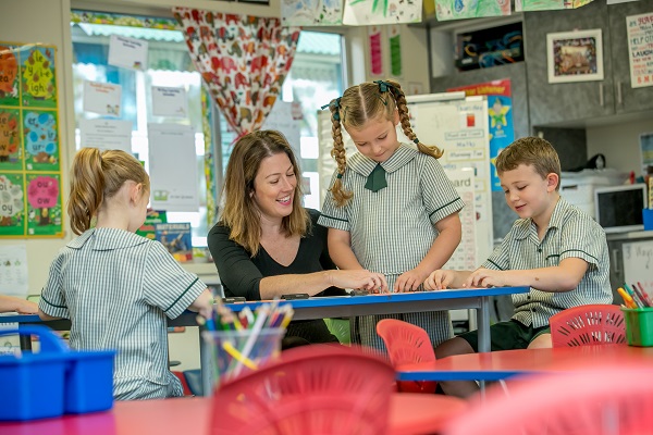 teacher working with three students at a table