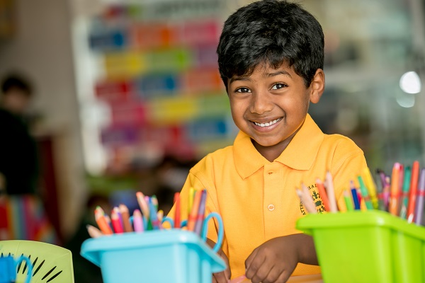 Prep student sitting at a desk with coloured pencils